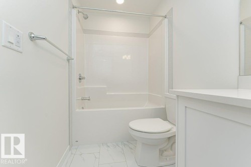 Bathroom featuring a white tub/shower combination, white toilet, white vanity with a light-toned countertop, and light-toned tile flooring - 6271 180 Avenue, Edmonton, AB - Indoor Photo Showing Bathroom