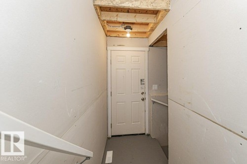 Stairwell with white six-panel door, light gray flooring, and wood beam ceiling - 6271 180 Avenue, Edmonton, AB - Indoor Photo Showing Other Room