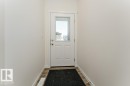 Entryway featuring a white paneled door with an upper glass insert, wood-finish flooring, and crisp white walls - 6271 180 Avenue, Edmonton, AB  - Indoor Photo Showing Other Room 