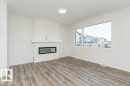 Spacious interior featuring wood-finish flooring, a contemporary fireplace with mantel, a large window, and recessed lighting - 6271 180 Avenue, Edmonton, AB  - Indoor With Fireplace 