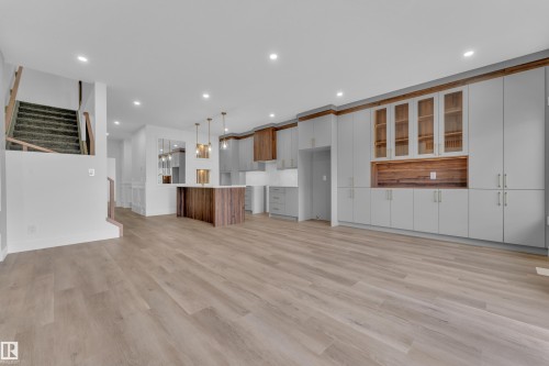 Open-concept living area featuring wide plank wood-finish flooring, recessed lighting, and a modern kitchen with a wood-finish island - 3116 8 Avenue, Edmonton, AB - Indoor Photo Showing Kitchen