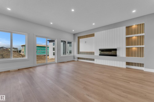 Spacious living area featuring wood-finish flooring, recessed lighting, and a contemporary media wall with an electric fireplace - 3116 8 Avenue, Edmonton, AB - Indoor Photo Showing Living Room With Fireplace
