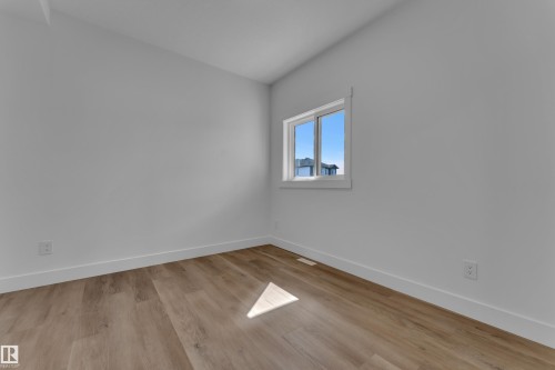 Room featuring wood-finish flooring, white baseboards, and a single window with white trim - 3116 8 Avenue, Edmonton, AB - Indoor Photo Showing Other Room