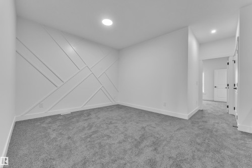 Bedroom featuring a textured accent wall with geometric paneling, recessed lighting, gray carpeting, white baseboards, and a doorway leading to an interior corridor - 3116 8 Avenue, Edmonton, AB - Indoor Photo Showing Other Room