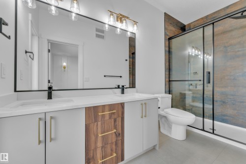Bathroom featuring a dual vanity with white countertops, integrated sinks, and a combination of wood-finish and white cabinetry - 3116 8 Avenue, Edmonton, AB - Indoor Photo Showing Bathroom
