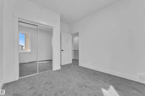 Bright interior room featuring a mirrored sliding closet door, neutral grey carpet, and white trim - 3116 8 Avenue, Edmonton, AB - Indoor Photo Showing Other Room