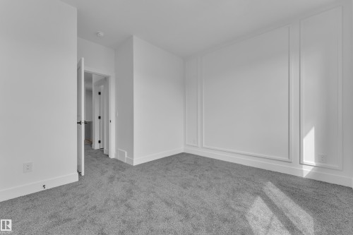 Room featuring decorative wall molding, plush grey carpeting, white baseboards, and a doorway with a dark-finished handle - 3116 8 Avenue, Edmonton, AB - Indoor Photo Showing Other Room