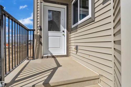 Entryway featuring a white door with upper glass panel, concrete porch, and black metal railing - 3116 8 Avenue, Edmonton, AB - Outdoor With Exterior