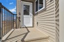Entryway featuring a white door with upper glass panel, concrete porch, and black metal railing - 3116 8 Avenue, Edmonton, AB  - Outdoor With Exterior 