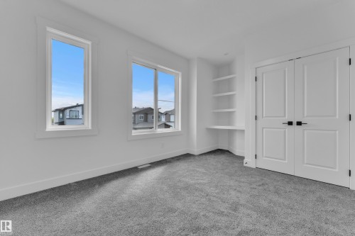Room featuring light gray carpet, multiple windows, built-in shelving, and white double doors with black hardware - 3116 8 Avenue, Edmonton, AB - Indoor Photo Showing Other Room