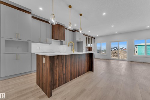 Contemporary kitchen featuring a large central island with wood-finish paneling and a white countertop - 3116 8 Avenue, Edmonton, AB - Indoor Photo Showing Kitchen