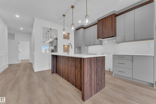 Contemporary kitchen featuring a large wood-finish island with a white countertop and brass-finish faucet - 3116 8 Avenue, Edmonton, AB - Indoor Photo Showing Kitchen With Upgraded Kitchen