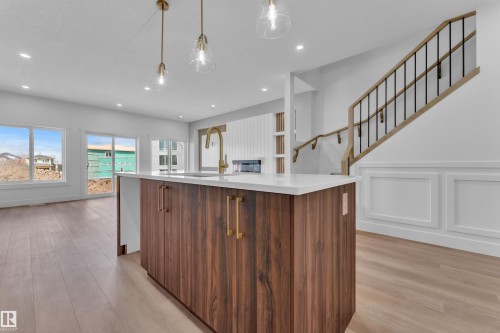 Kitchen island featuring wood-finish cabinetry, a white countertop, and a gooseneck faucet - 3116 8 Avenue, Edmonton, AB - Indoor Photo Showing Kitchen