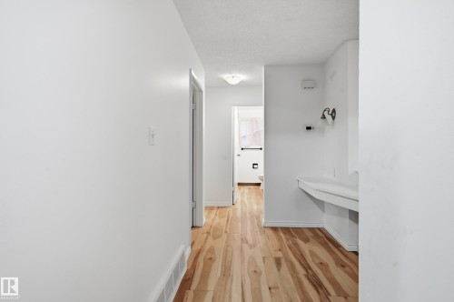 Hallway featuring wood-finish flooring, white walls, and a built-in vanity with wall-mounted sconce lighting - 13903 87 Street, Edmonton, AB - Indoor Photo Showing Other Room