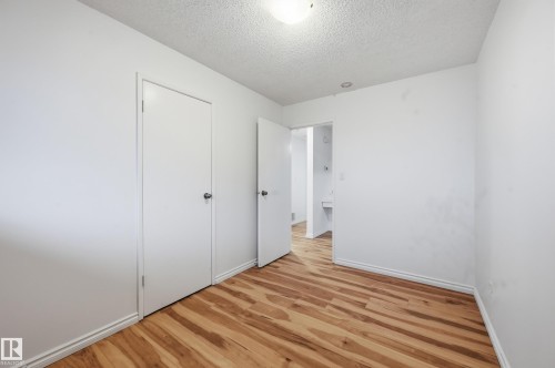 Bedroom featuring wood-finish flooring, two white doors with round hardware, and a single ceiling light fixture - 13903 87 Street, Edmonton, AB - Indoor Photo Showing Other Room
