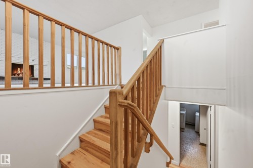 Hardwood staircase with natural wood balusters and handrails, leading to a lower level with a visible laundry area - 13903 87 Street, Edmonton, AB - Indoor Photo Showing Other Room