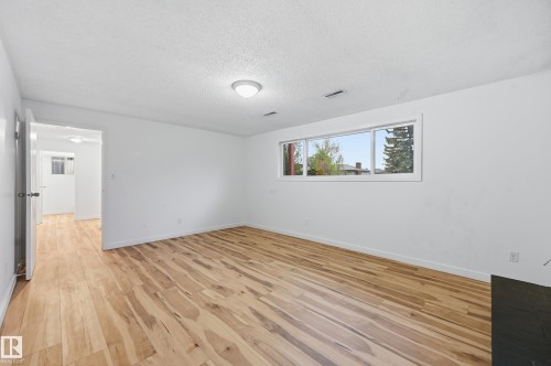 Spacious room featuring light wood-finish flooring, white painted walls, and a large horizontal window providing natural illumination - 13903 87 Street, Edmonton, AB - Indoor Photo Showing Other Room