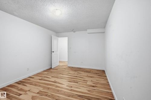Room featuring wood-finish flooring, white baseboards, and bright white walls - 13903 87 Street, Edmonton, AB - Indoor Photo Showing Other Room