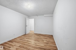 Room featuring wood-finish flooring, white baseboards, and bright white walls - 