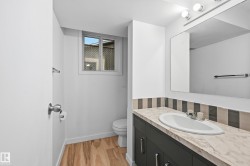 Bathroom featuring a vanity with a light-toned countertop, integrated sink, and dark cabinetry with silver-toned hardware - 