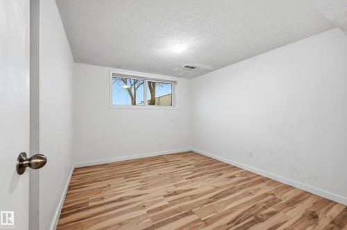 Room featuring wood-finish flooring, white baseboards, and a window with white trim - 13903 87 Street, Edmonton, AB - Indoor Photo Showing Other Room