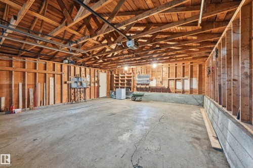 Spacious garage with exposed wood beam ceiling, concrete flooring, and built-in shelving - 13903 87 Street, Edmonton, AB - Indoor Photo Showing Garage