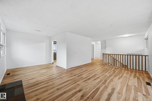 Spacious open-concept living area featuring wood-finish flooring, crisp white walls, and abundant natural light from multiple windows - 13903 87 Street, Edmonton, AB - Indoor Photo Showing Other Room