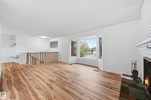 Spacious interior with wood-finish flooring, a white brick fireplace, and a bay window - 13903 87 Street, Edmonton, AB - Indoor With Fireplace