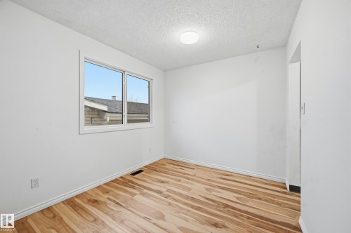 Bright interior room featuring a large window, light wood-finish flooring, white walls, white baseboards, and a flush-mount ceiling light fixture - 13903 87 Street, Edmonton, AB - Indoor Photo Showing Other Room