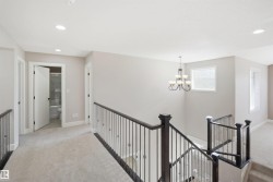 Upper-level landing featuring a staircase with dark wood newel posts and wrought iron balusters - 