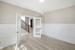 Bright room featuring light wood-finish flooring and extensive white wainscoting - 