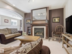 Living area featuring a fireplace with a wood mantle, a large mirror, and recessed lighting - 