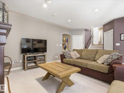 Carpeted living area featuring recessed lighting, a built-in media console, and a staircase with a wood railing - 