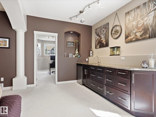 Built-in wet bar featuring dark wood-finish cabinetry, a granite-finish countertop, and a stainless steel under-counter refrigerator - 1340 Oakland Crescent, Devon, AB - Indoor Photo Showing Other Room