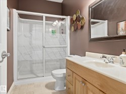 Bathroom featuring a shower with sliding doors, a white toilet, and a light wood-finish vanity with a white countertop and integrated sink - 