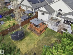 Expansive backyard featuring a large elevated wood deck with white railing, covered gazebo, additional lower wood deck, and a manicured lawn - 