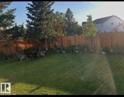 Expansive backyard featuring a lush lawn, wood privacy fencing, mature trees, and established perimeter landscaping - 