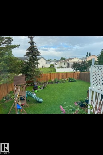 Expansive backyard featuring a lush lawn, wood privacy fencing, and established garden beds - 1340 Oakland Crescent, Devon, AB - Outdoor With Backyard