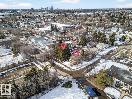 Aerial view showcasing the surrounding neighborhood, featuring a mix of residential properties with varied rooflines and a distant skyline - 12942 68 Street, Edmonton, AB 