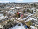 Aerial view showcasing the surrounding neighborhood, featuring a mix of residential properties with varied rooflines and a distant skyline - 12942 68 Street, Edmonton, AB 