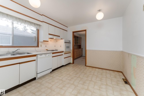 Kitchen featuring white cabinetry with wood trim, a built-in wall oven, a dishwasher, and a double basin sink - 3711 118 Street, Edmonton, AB - Indoor Photo Showing Kitchen With Double Sink
