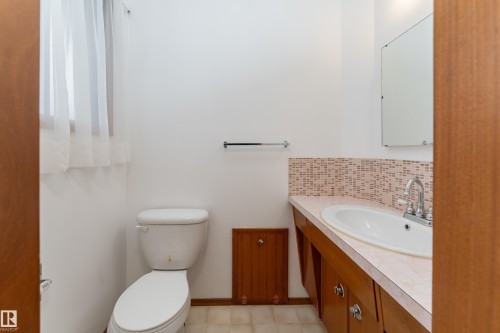 Bathroom featuring a single vanity with built-in cabinetry, an integrated sink, and a tiled backsplash - 3711 118 Street, Edmonton, AB - Indoor Photo Showing Bathroom