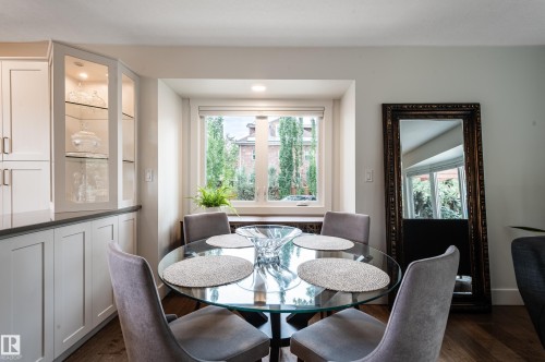 Dining area featuring a built-in cabinet with glass-front display, ample natural light from the window, recessed ceiling lighting, and wood-finish flooring - 14604 92A Avenue, Edmonton, AB - Indoor Photo Showing Dining Room