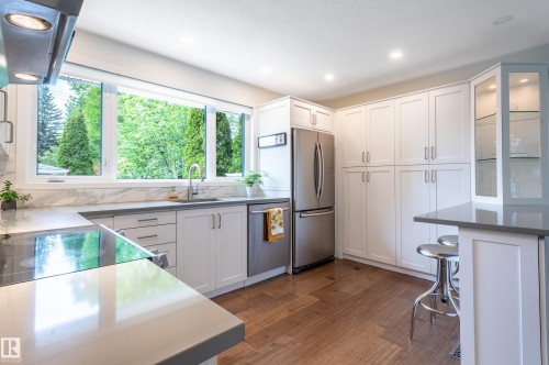 Modern kitchen featuring white shaker cabinetry, stainless steel appliances, and wood-finish flooring - 14604 92A Avenue, Edmonton, AB - Indoor Photo Showing Kitchen