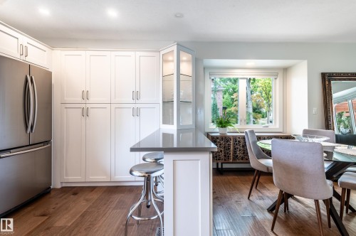 Kitchen featuring white shaker cabinetry, stainless steel refrigerator, dark wood-finish flooring, a functional island with a gray countertop, and recessed lighting - 14604 92A Avenue, Edmonton, AB - Indoor