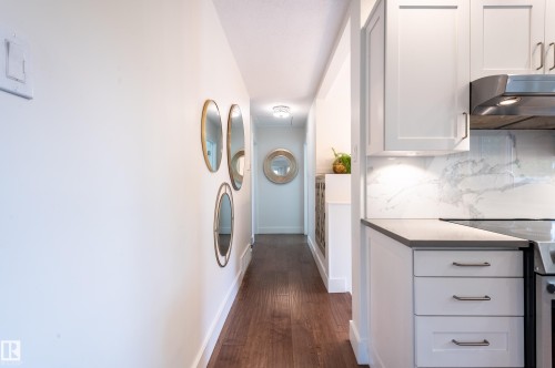 Kitchen cabinetry with an integrated cooktop, stone-finish countertop, and a full-height stone-finish backsplash - 14604 92A Avenue, Edmonton, AB - Indoor Photo Showing Laundry Room