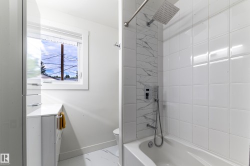 Modern bathroom featuring a soaking tub, white subway tile surround, rain shower head, and a vanity with an integrated sink - 14604 92A Avenue, Edmonton, AB - Indoor Photo Showing Bathroom