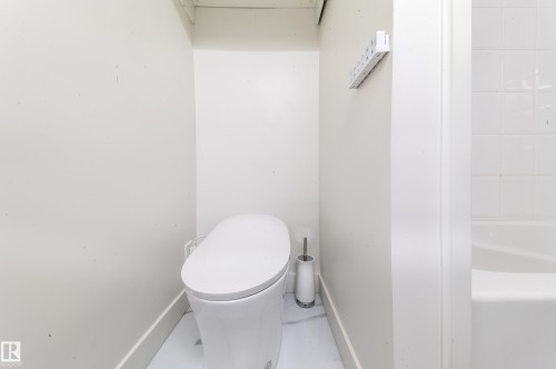 Contemporary white toilet with a sleek, elongated bowl and concealed trapway - 14604 92A Avenue, Edmonton, AB - Indoor Photo Showing Bathroom