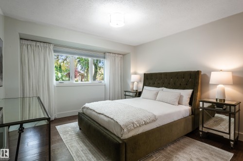Bedroom featuring dark wood-finish flooring, a large window with white drapery, and a contemporary ceiling light fixture - 14604 92A Avenue, Edmonton, AB - Indoor Photo Showing Bedroom