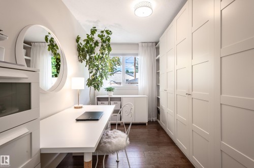 Bright room featuring extensive built-in cabinetry, wood-finish flooring, a contemporary ceiling light fixture, and a window with white sheer curtains - 14604 92A Avenue, Edmonton, AB - Indoor
